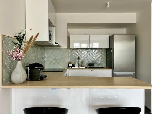 une cuisine avec des placards blancs et un comptoir avec un vase de fleurs dans l'établissement Élégant Appartement Minimaliste entre Paris et Disney, à Noisy-le-Grand
