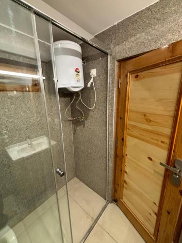 a shower with a glass door in a bathroom at The Cocoon in Dehradun