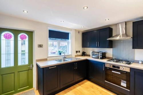 a kitchen with black cabinets and a green door at Quaint listed home in Barton in Barton-upon-Humber