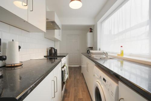 a kitchen with white cabinets and a black counter top at Grimsby City Centre stay in Grimsby