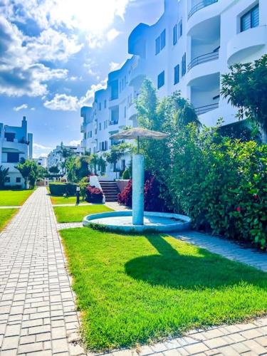 a fountain in the grass next to a building at Superbe appartement vue sur mer in Marina Smir