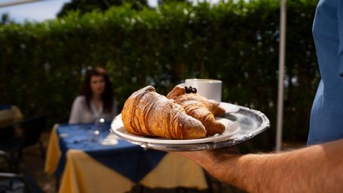 a person holding a plate with croissants on it at Boutique San Daniele in Cirella