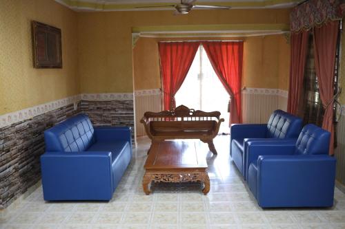 a living room with two blue couches and a piano at Seri Tempurung Homestay in Cukai