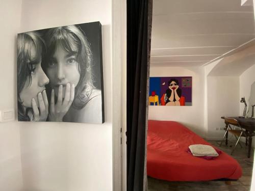 - une chambre avec un lit rouge et des photos sur le mur dans l'établissement Studio proche de la mer, à Marseille