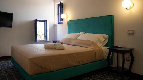 a bedroom with a large bed with a green headboard at Boutique San Daniele B&B in Cirella