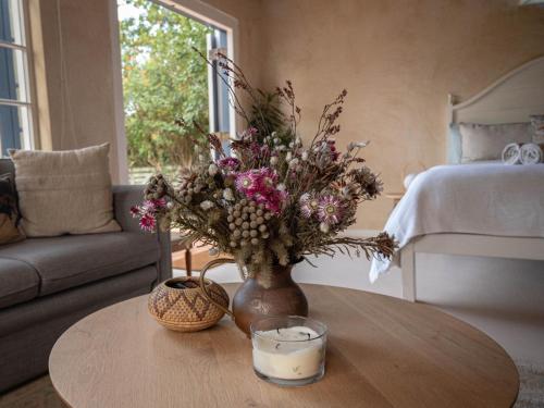 a vase with flowers on a table in a living room at Cape Weaver cottage in Greyton