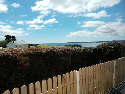 a fence in front of a house next to the water at Cozy seaside cottage in Wexford