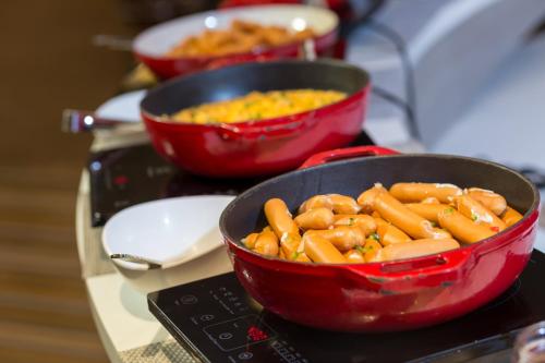 two red bowls of food sitting on top of a stove at Cassia Phuket, part of Banyan Group in Bang Tao Beach