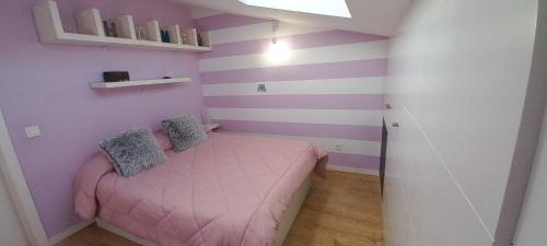 a small bedroom with a pink bed and purple stripes at Ático con 2 dormitorios y garaje a 10 minutos de Valladolid in Valladolid