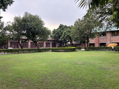 a person with an umbrella sitting in a field in front of a building at The Cocoon in Dehradun