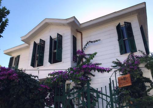 a white house with green shuttered windows and purple flowers at No16 Ada in Adalar