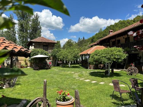 a yard with chairs and tables and a building at Konak Tosa in Poganovo