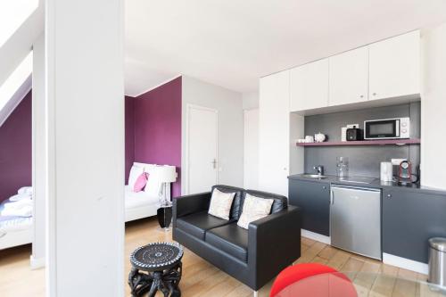 un salon avec une chaise noire et une cuisine dans l'établissement GuestReady -Cozy Apartment with Eiffel Tower view, à Paris