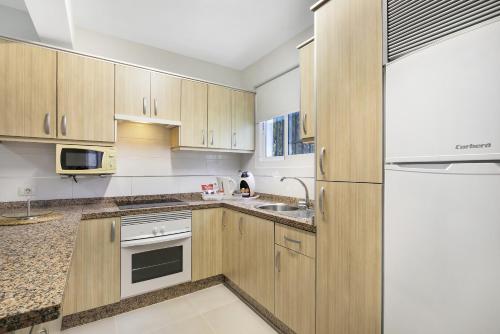 a kitchen with wooden cabinets and a refrigerator at Aguaviva Perfect Holiday in Callao Salvaje