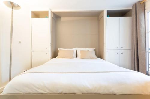 - une chambre avec un grand lit et des placards blancs dans l'établissement GuestReady-Designer Studio for 2, close to Louvre!, à Paris