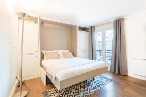 une chambre avec un lit et une grande fenêtre dans l'établissement GuestReady-Designer Studio for 2, close to Louvre!, à Paris