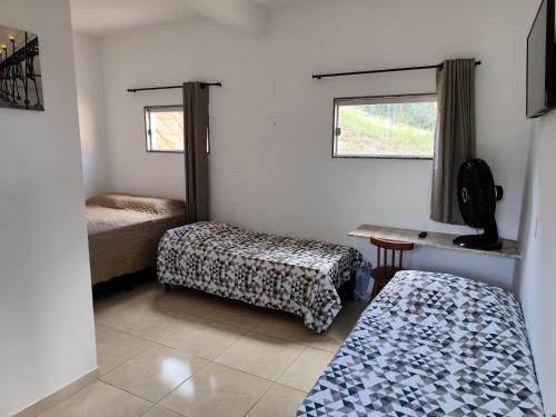 a room with two beds and a table and a window at Pousada Chácara Pau - Brasil in Lagoa Sêca