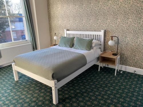 a bedroom with a white bed with blue pillows and a window at The Bell Inn in Evercreech