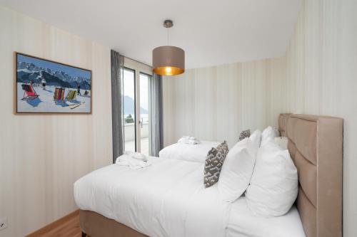 a bedroom with a large white bed and a window at Montreux Four Bedroom Penthouse by Swiss Hotel Apartments in Montreux