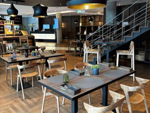 restauracja ze stołami i krzesłami oraz schodami w obiekcie Novotel Vilnius Centre w Wilnie