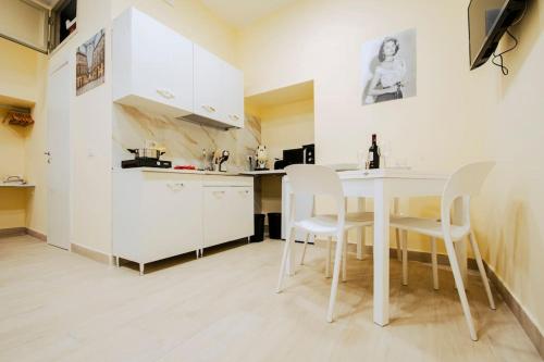 una cucina con un tavolo bianco e sedie bianche di Basso ai Quartieri experience a Napoli