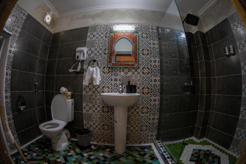 a bathroom with a sink and a toilet and a mirror at Riad Taj Fes in Fès