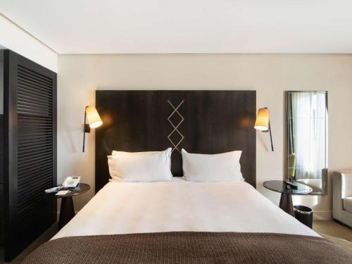 a hotel room with a large bed with two tables at Sofitel Montevideo Casino Carrasco & Spa in Montevideo