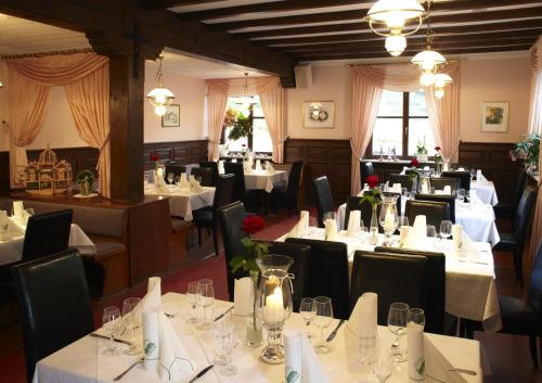 un comedor con mesas y sillas con manteles blancos en Hotelgasthof Buchenmühle, en Lohr