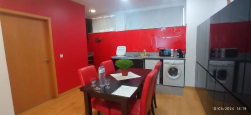 a kitchen with red walls and a table with red chairs at APART 2 Alojamento Para Turismo e Negócios in Braga