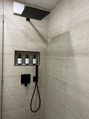 a bathroom with a shower with three bottles on a shelf at Thê Rath Residence in Düsseldorf