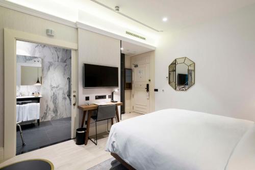 a bedroom with a bed and a desk and a tv at DoubleTree by Hilton Madrid-Prado in Madrid