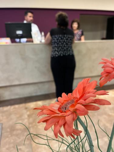 a woman standing at a counter behind a red flower at Gregorio I Hotel Boutique in San Salvador de Jujuy
