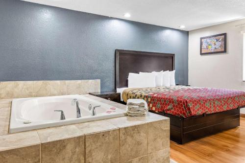a hotel room with a tub and a bed at Econo Lodge Akron Copley Northwest in Montrose
