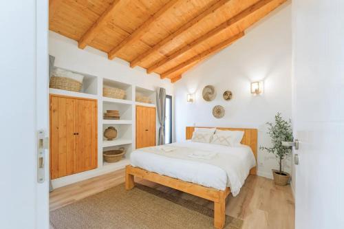 a bedroom with a white bed and wooden ceilings at Esteva CountryHouse in Rogil
