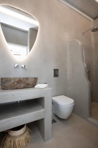 a bathroom with a sink and a toilet and a mirror at Sunrise Villa - Sea View Private Pools in Mikonos