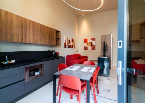 a kitchen with a table and red chairs in a room at Le Stanze di Gianmarmo - Galleria 41037 in Mirandola