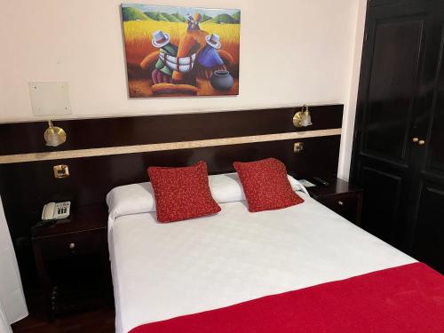 a bedroom with a bed with red pillows and a painting at Gregorio I Hotel Boutique in San Salvador de Jujuy