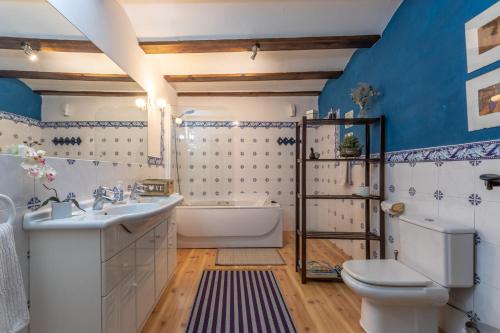 a bathroom with blue walls and a white tub and sink at Peregrinando, pensión con encanto in Navarrete