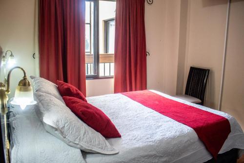 a bedroom with a bed with red curtains and a window at Gregorio I Hotel Boutique in San Salvador de Jujuy