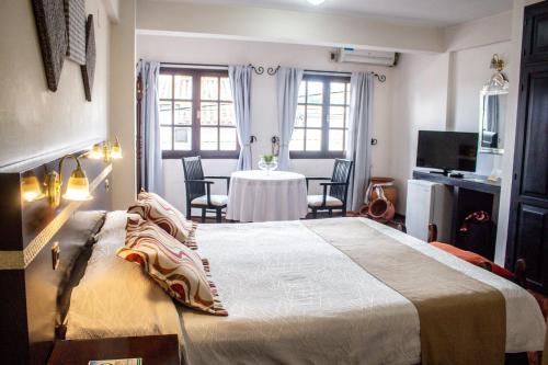 a bedroom with a large bed and a table with chairs at Gregorio I Hotel Boutique in San Salvador de Jujuy