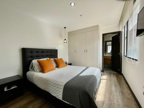 a bedroom with a large bed with orange pillows at &ARBAT Quito Republlica del Salvador Alquiler por días in Quito