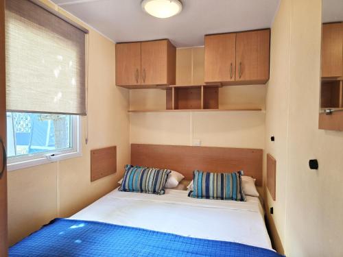 a small bedroom with a bed and a window at Camping Costa Dorada Bungalow Maia in Canet de Mar