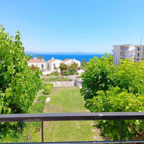 a balcony with a view of a yard and the ocean at village club 24 summer dream home in Nea Fokea