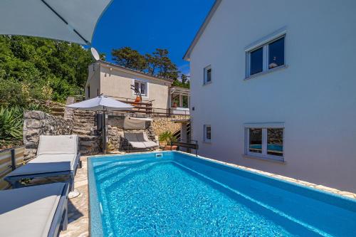 a swimming pool in front of a house with an umbrella at Hot Tub, Pool & Stunning View #Guest House Stella# in Dramalj