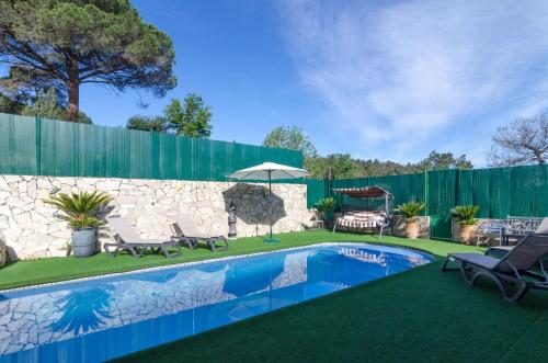 a backyard with a swimming pool and a stone fence at Club Villamar - Filo in Maçanet de la Selva