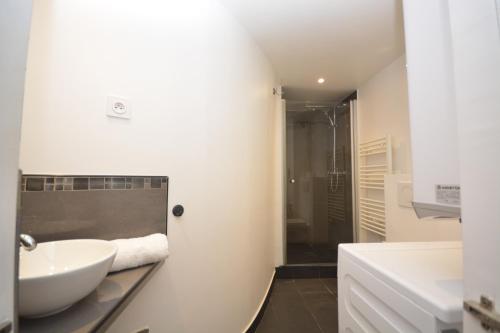 une salle de bain blanche avec un lavabo et une douche dans l'établissement Studio Opera-Bourse, à Paris