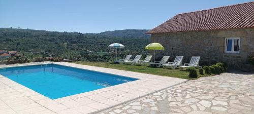 a swimming pool next to a house with chairs and umbrellas at Quinta do Cruzeiro in Mata