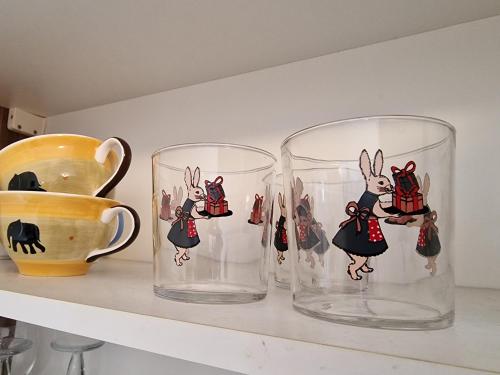 two glasses sitting on a shelf next to a vase at Zajček Apartma in Mojstrana