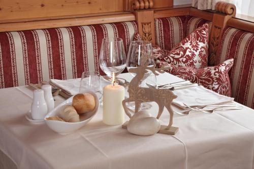 a table with a white table cloth with a candle and wine glasses at Hotel Colbricon Beauty & Relax in San Martino di Castrozza