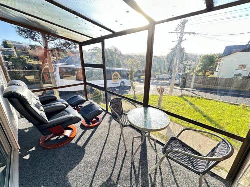 a screened in porch with chairs and a table at Glenpark Lodge in Dunedin